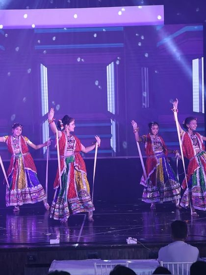 This stage performance showcases a dandiya routine with intricate patterns and formations, enhanced by professional stage lighting.