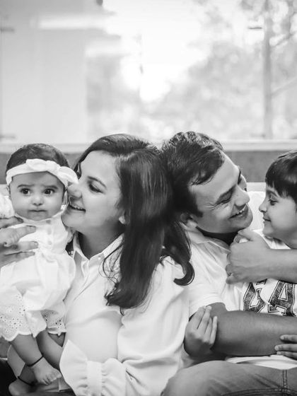 A tender black and white moment, with the mother kissing her baby girl while the father and son look on.