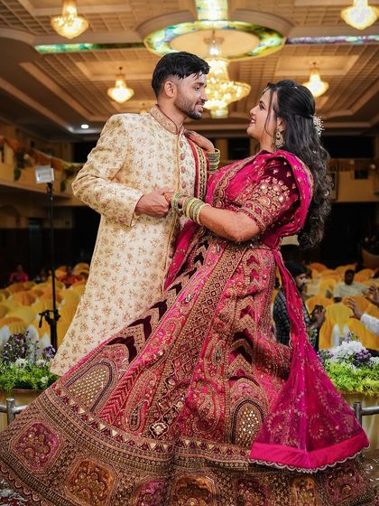 A fairytale moment for the couple at their reception. The bride's elaborate pink lehenga is complemented by a dramatic makeup look.