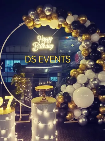 My services are not just for kids. I create chic and modern setups for milestone birthdays, like this 27th birthday party on a rooftop. The black, gold, and silver balloon arch, neon sign, and light-up marquee numbers create a sophisticated party atmosphere.