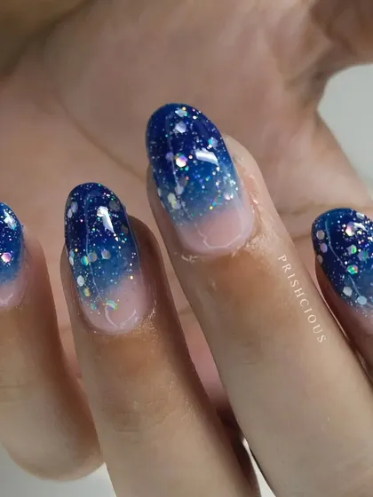 Get your nails festival-ready with this blue glitter ombré. This design was done with gel polish on the client's own natural nails.