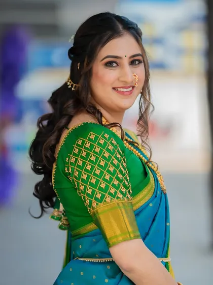 A side profile showing the elegant half-up, half-down hairstyle with soft curls, which is a popular choice for modern Maharashtrian brides.
