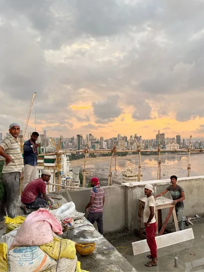 A team of workers on the rooftop of our Walkeshwar project. This image captures the collaborative spirit on-site, with the expansive Mumbai cityscape providing a dramatic backdrop to the construction process.