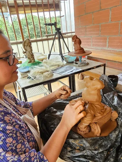 A student works on her Ganesha idol with a tripod set up, perhaps capturing her own creative process.