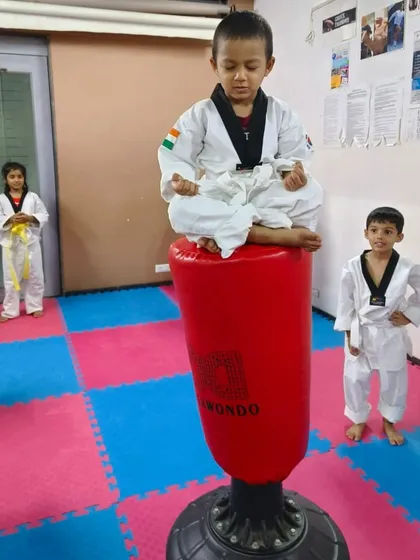 A powerful image of a 3-year-old athlete meditating on top of a punching bag. This demonstrates incredible balance and focus, showing that mental wellness is as important as physical training in my academy.