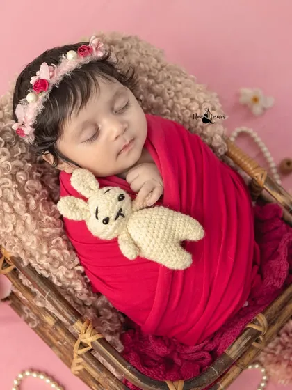 A sweet portrait of a newborn cuddling a small knitted bunny. Using props like these adds a touch of personality and scale to the photos.