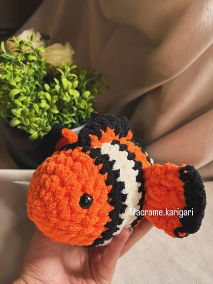 Holding our handmade clownfish toy. It's made with soft chunky yarn, making it a safe and fun toy for kids.