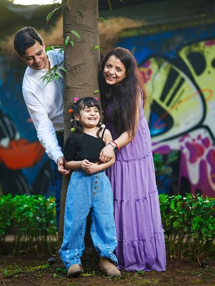 A playful game of peek-a-boo around a tree makes for a fun and candid family photo against a colorful graffiti wall.