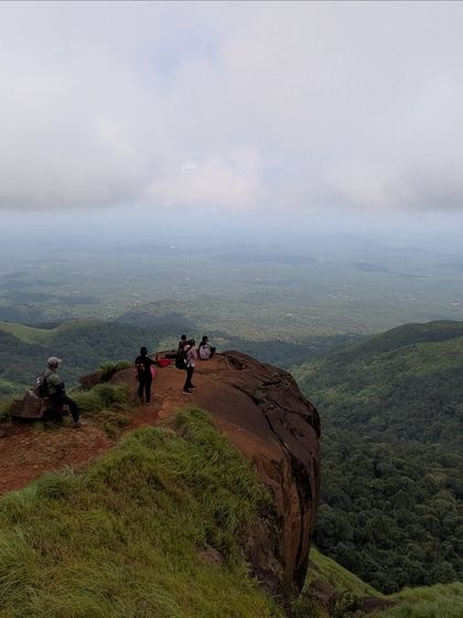 A trekker on the edge of a cliff at Kurinjal, with a vast valley below. The views are simply epic.