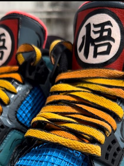 A close up of the custom laces and tongue detail on the Dragon Ball Z Air Jordan 4s. The laces are dyed to match Goku's uniform, and the tongue features his iconic 'Go' symbol.