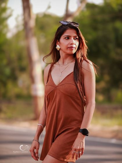 A full-body shot that captures a sense of movement and purpose. The outdoor setting and her confident stride tell a story of a woman on a journey.