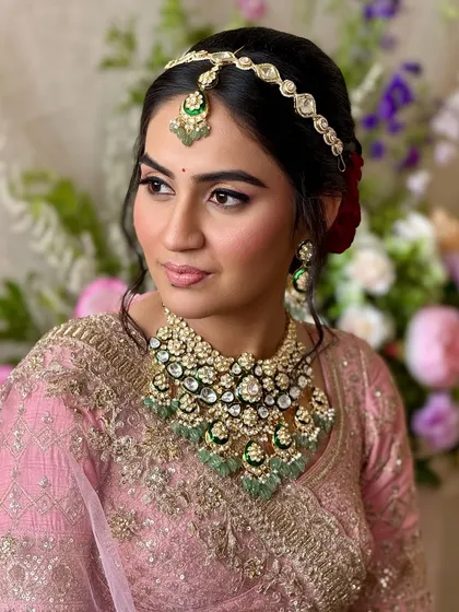 A portrait of the bride looking radiant and confident. The makeup is designed to enhance her features and complement her stunning emerald jewelry.