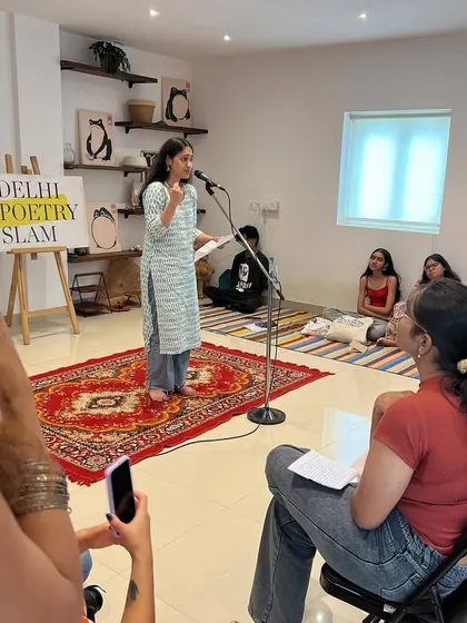 A poet performs her piece as an audience member captures the moment on her phone.