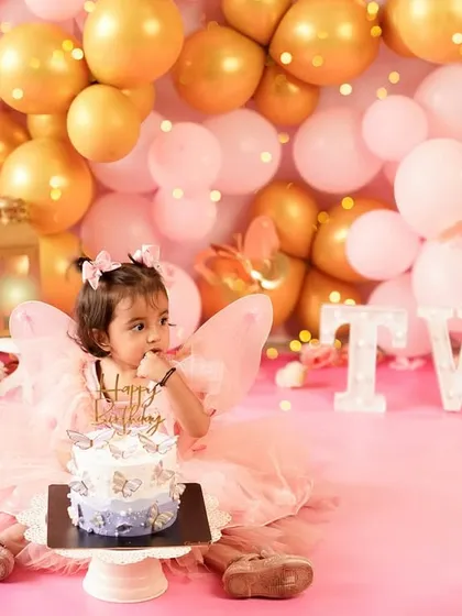 The moment before the smash. This little girl eyes her beautiful butterfly-adorned cake, ready to celebrate turning two in style.