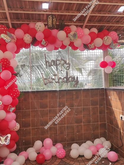 A lovely outdoor birthday setup with a red and pink balloon arch.