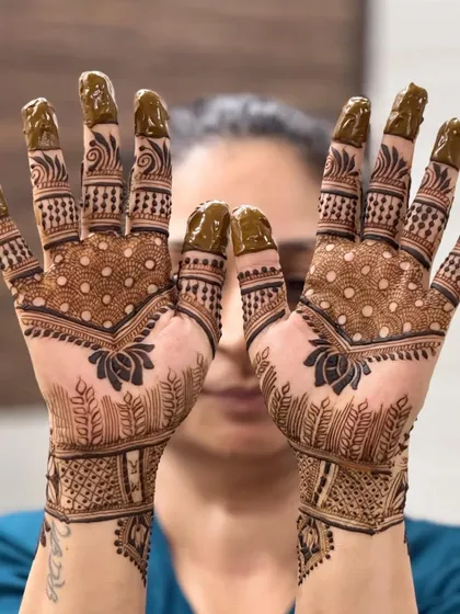 Candid mehendi photos are the best! This design features a dotted pattern on the palm with a lotus motif, creating a look that is both modern and rooted in tradition.