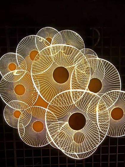 A modern, artistic ceiling light fixture with intricate engraved patterns.