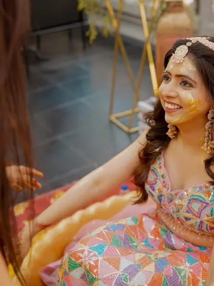 The bride's radiant smile during her Haldi ceremony. The colorful lehenga and simple floral jewelry are perfect for this fun-filled event.
