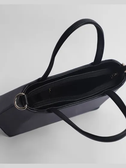 A top-down view of an open black handbag, showing the dark interior and compartments.