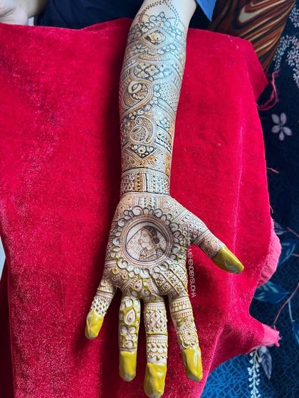A full arm view of Sonali's bridal mehendi, showing how the portrait is balanced with intricate patterns extending up to the elbow.