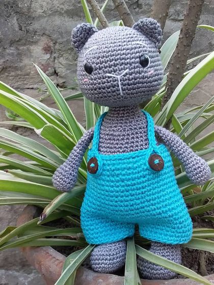 Meet Coal the Kitten, a sweet little cat amigurumi wearing bright blue overalls. He's ready for a day of play in the garden.