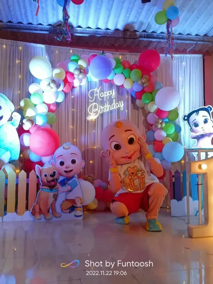A complete Cocomelon theme setup for a first birthday. We used a colorful pastel balloon arch, character cutouts of JJ and his friends, a light-up number '1', and a neon sign to create this cheerful backdrop.
