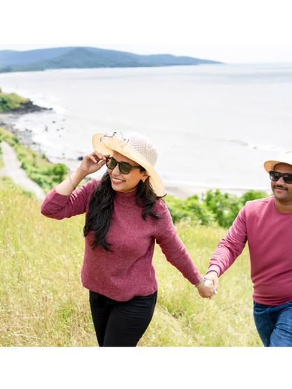 A couple enjoys a scenic walk during their pre-wedding shoot, with the beautiful coastline in the background.