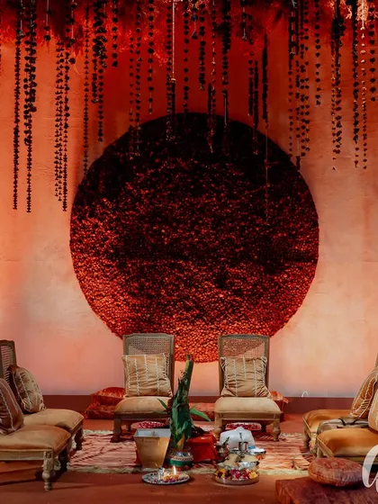 We designed this seating arrangement for a wedding ceremony with a dramatic circular floral backdrop made of red carnations. The setup provides a beautiful focal point for the couple while ensuring guests are comfortable and have a perfect view of the proceedings.