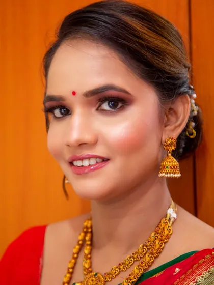 A close-up of the final makeup look. The skin is luminous, and the eyes are defined with warm, shimmery tones.