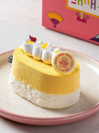 A mango mousse mini cake with a delicate white chocolate logo, showcasing a light and fruity dessert option.