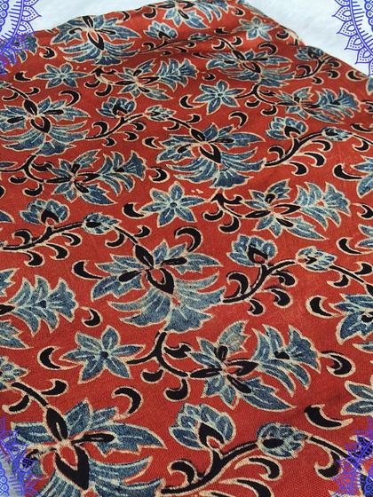 This red Ajrakh fabric features a beautiful floral vine pattern in shades of blue and black. It's an excellent choice for stitching a statement kurti or dress.
