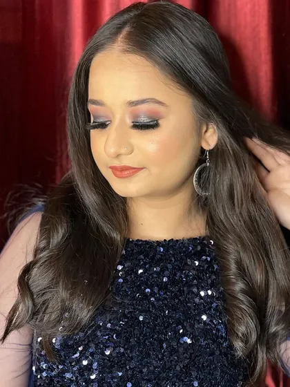 A close-up of a party look with a blue sequined top. The eye makeup has hints of silver and smoke to complement the outfit perfectly.