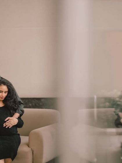 A moody and artistic indoor maternity portrait. The reflection in the glass adds a layer of depth and thoughtfulness to this intimate moment.