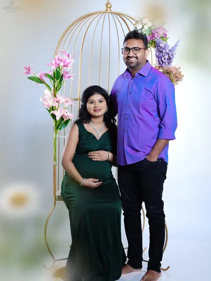 This classic studio portrait shows a couple sharing a happy moment before their baby arrives. We use elegant props like this golden birdcage chair to add a touch of sophistication to your maternity photos.