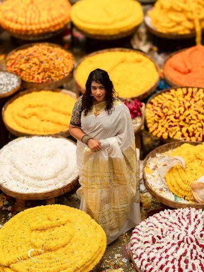 A wide shot that captures the overwhelming beauty and color of the flower market. She stands as a calm, elegant figure amidst the joyful chaos.