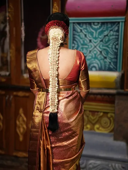 A bridal hairstyle is a crown. Here, you can see the detail of a traditional South Indian jada, intricately woven and adorned with fresh jasmine flowers and classic hair jewels.