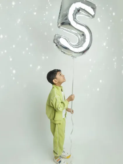 A thoughtful and artistic shot of the five-year-old looking up at his balloon, a moment of childhood wonder.