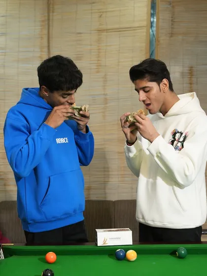 Good food, great company, and even better vibes. This picture shows two friends enjoying our wholesome sandwiches over a game of pool.