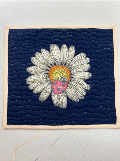 A smaller square placemat or mug rug with a single daisy and a ladybug.