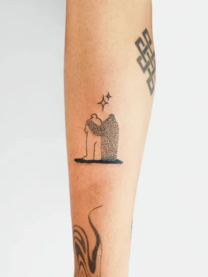 A minimalist and abstract tattoo depicting a figure being embraced by its own shadow. This conceptual piece uses dotwork to create a beautiful contrast and deep meaning.