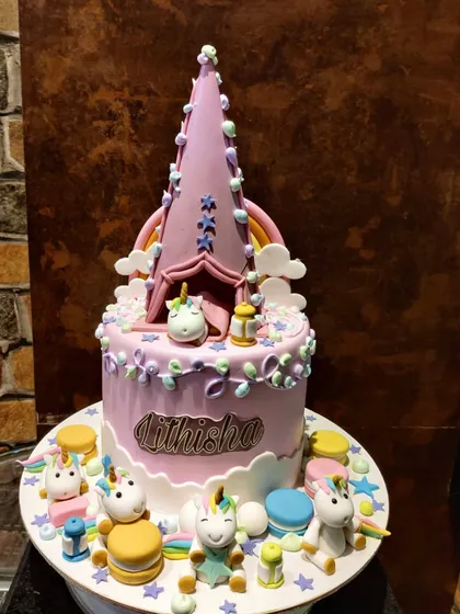 A closer look at my unicorn campsite cake. The design features a tall, pointed tent topper and several small, detailed unicorn figures enjoying a party at the base of the cake.