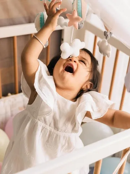 Babies are happiest in their natural habitat. This little one, playing with her crib mobile, shows how in-home sessions allow children to be themselves, resulting in genuine and soulful photos.