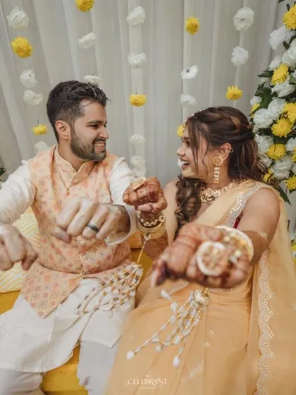 A playful moment from the Haldi ceremony, with the couple's hands adorned with flowers and henna.