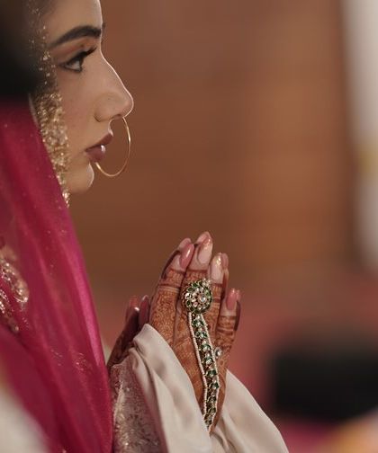 A prayerful moment. This side profile highlights her defined eye makeup and the beautiful details of her henna and jewellery.