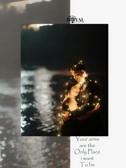 A romantic night shot of a couple wrapped in fairy lights, creating a warm and intimate glow by the water.