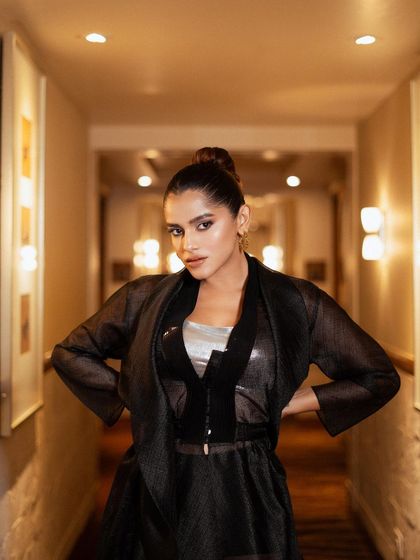 A strong, centered portrait. The model's powerful stance and direct gaze command attention, showcasing the structured yet fluid design of the ensemble.