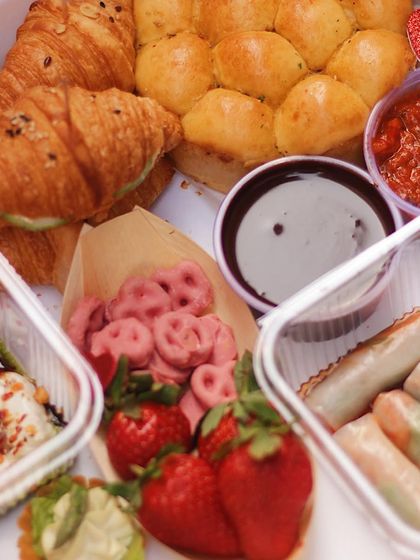 A close-up of the Valentine's box, showing the flaky croissants, pink pretzels, and fresh strawberries.