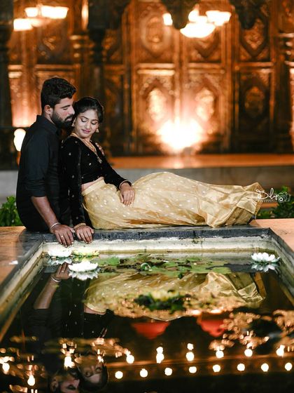 A beautiful reflection shot in the water, capturing the couple and the warm lights of the grand doorway behind them.