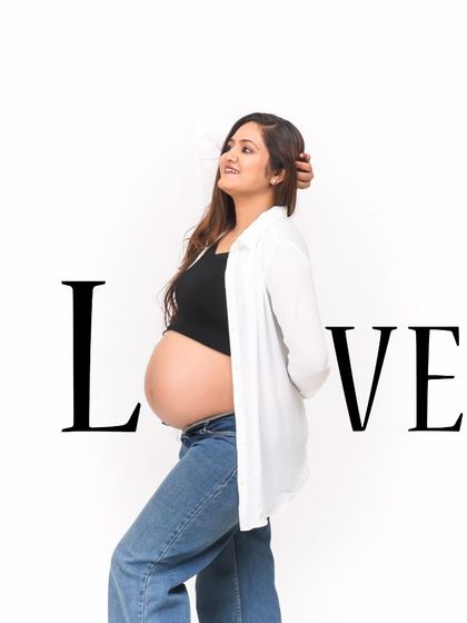 A stylish and modern maternity shot with a "LOVE" text overlay. The mom-to-be's casual outfit of jeans and an open shirt creates a relaxed and confident vibe.