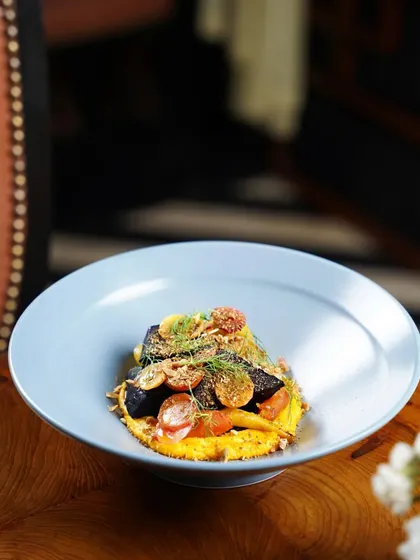 An elegantly plated fish dish from a fine dining restaurant. The soft lighting and shallow depth of field focus on the intricate details of the dish, conveying a sense of luxury.